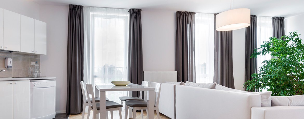 A bright living room with long curtains and white furniture